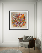 Framed abstract artwork on a wall above a chair with a gray cushion.