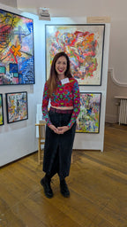 Woman standing in front of colorful abstract art in an exhibition setting
