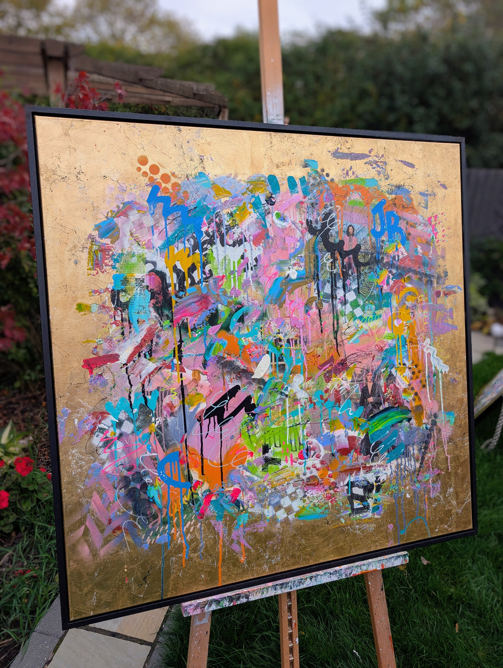 Colorful abstract painting on a gold background displayed outdoors.