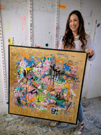 Woman holding a large abstract painting with colorful patterns in a room with white walls.