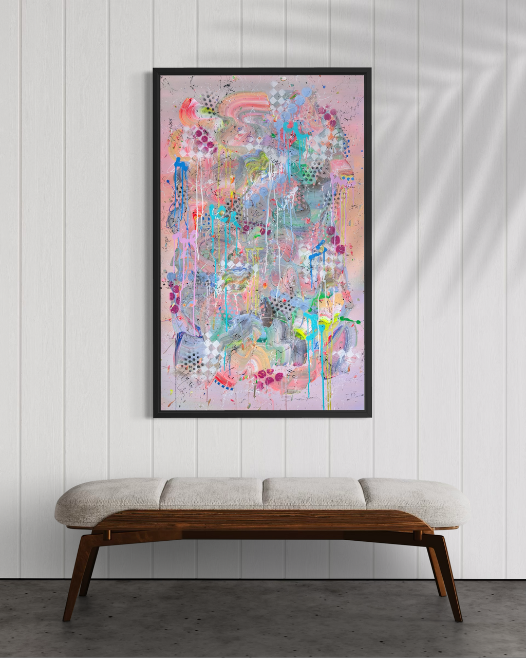 Colorful abstract painting on a white wall above a wooden bench.
