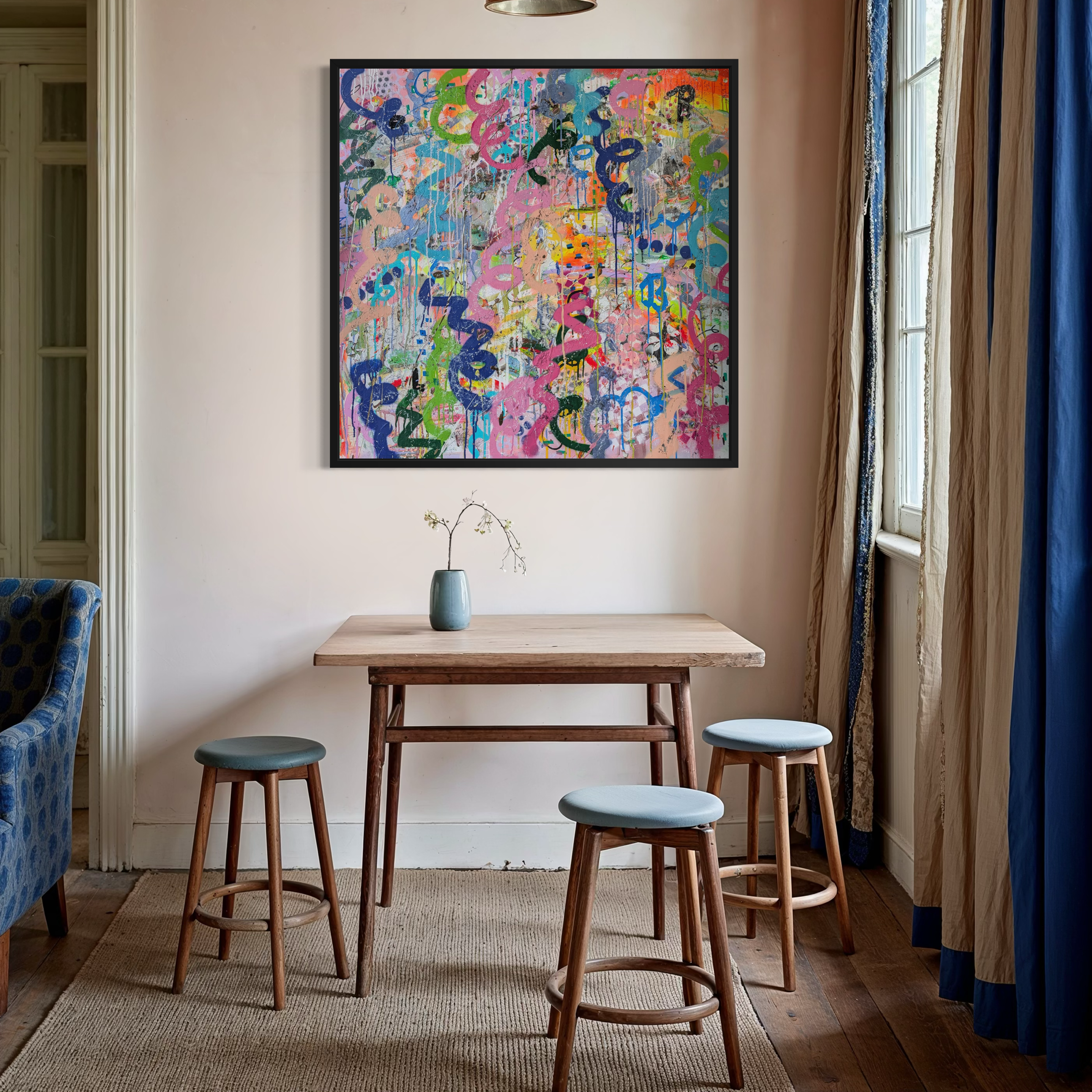 Dining area with a wooden table and stools, colourful abstract painting on the wall, and blue chair.