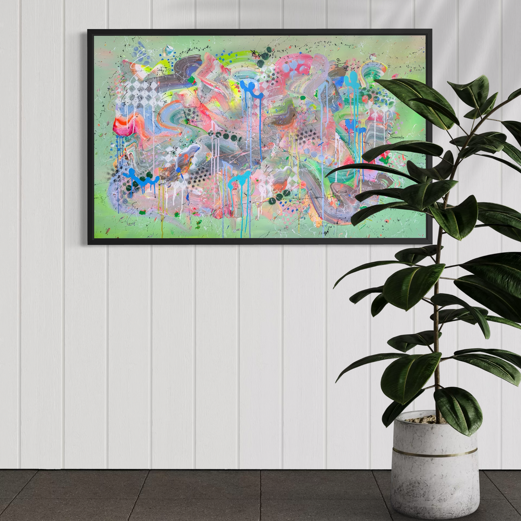 Colorful abstract painting in a black frame on a white wall with a plant to the right.