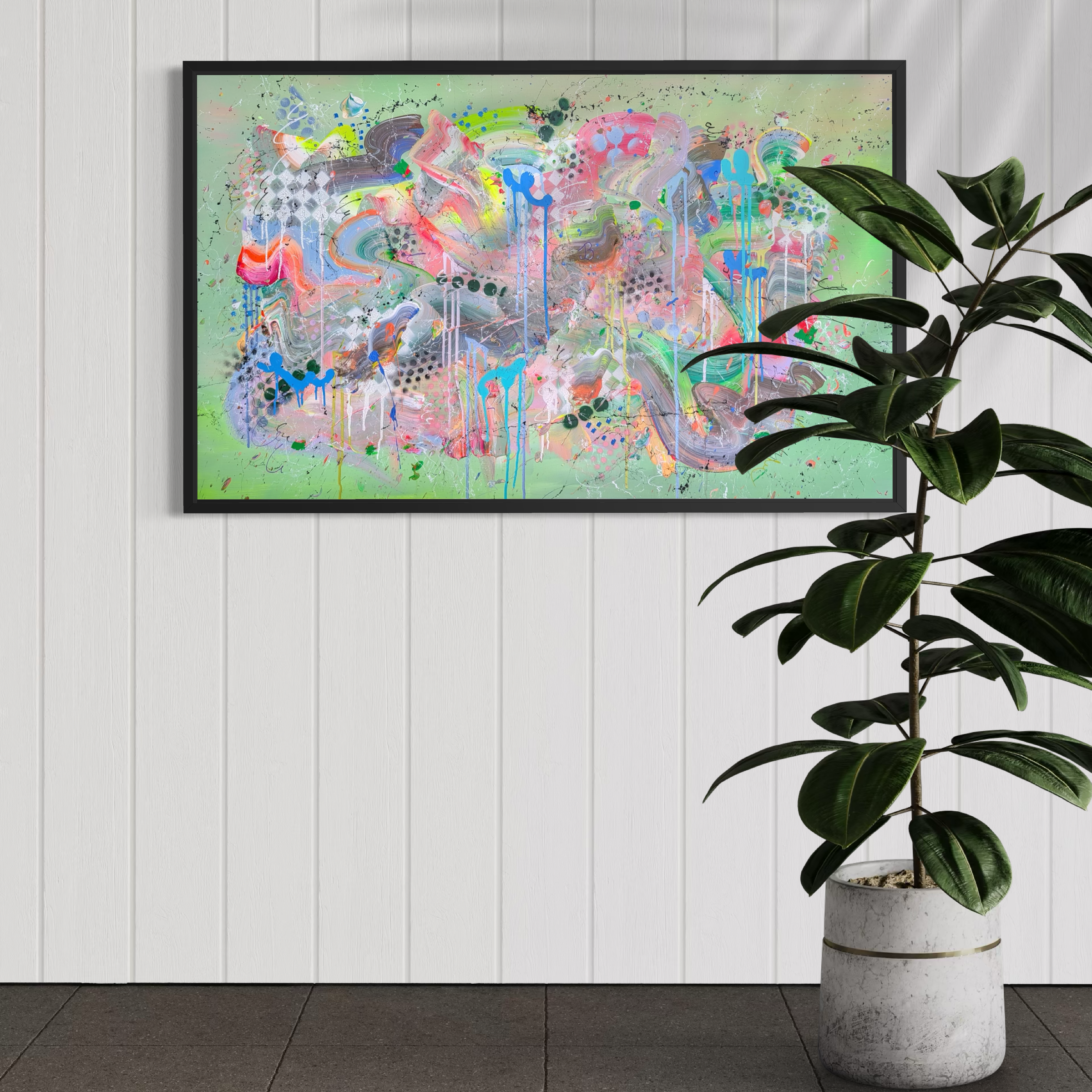 Colorful abstract painting in a black frame on a white wall with a plant to the right.