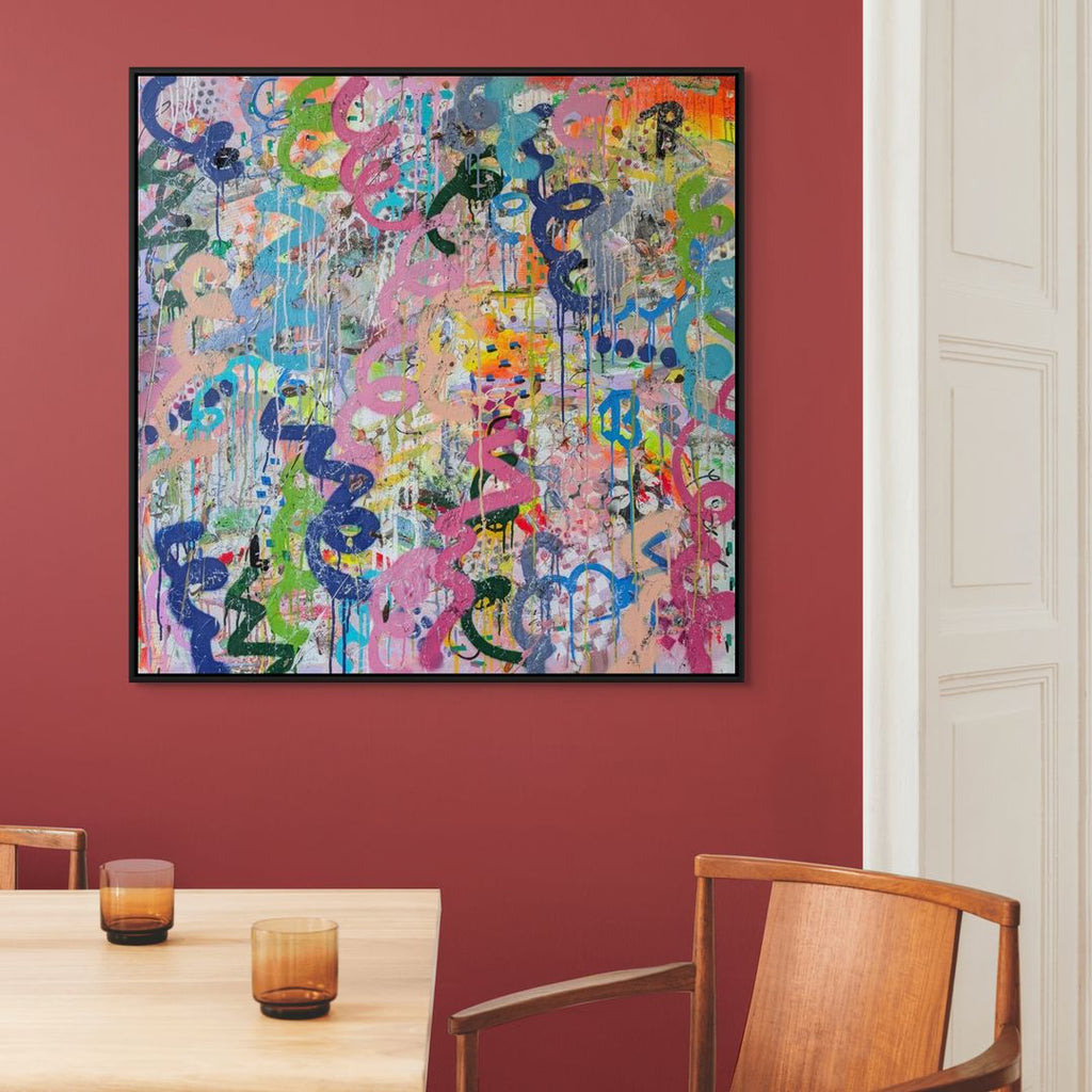 Colourful abstract painting on a red wall above a wooden table with glasses.